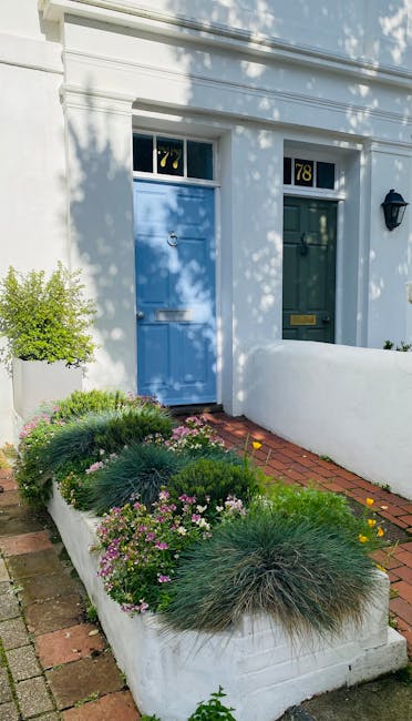 The image depicts the front garden of a property with a vibrant blue door featuring glass panels and a brass mail slot, set within a white arched frame. The garden is well-maintained, showcasing a var